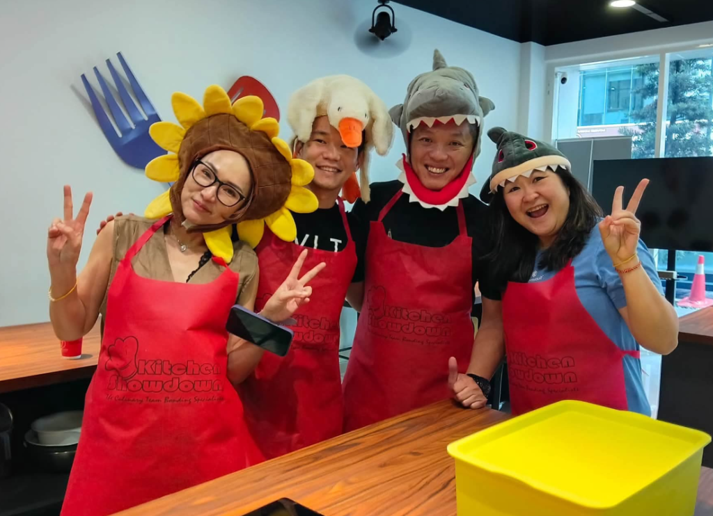 Corporate group in red aprons celebrating their cooking challenge dish at a festive team building event